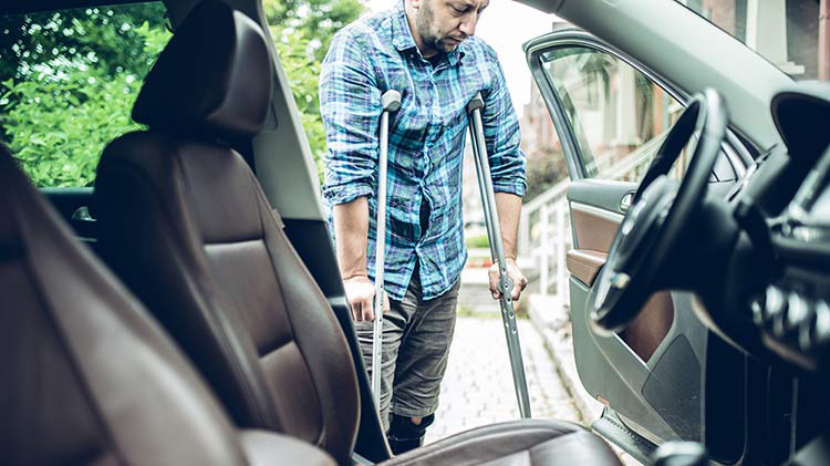 Man on crutches enters his car and is thankful he has Personal Injury Protection.