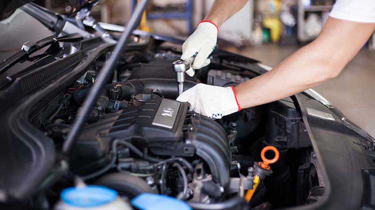 Mechanic working under a car hood.