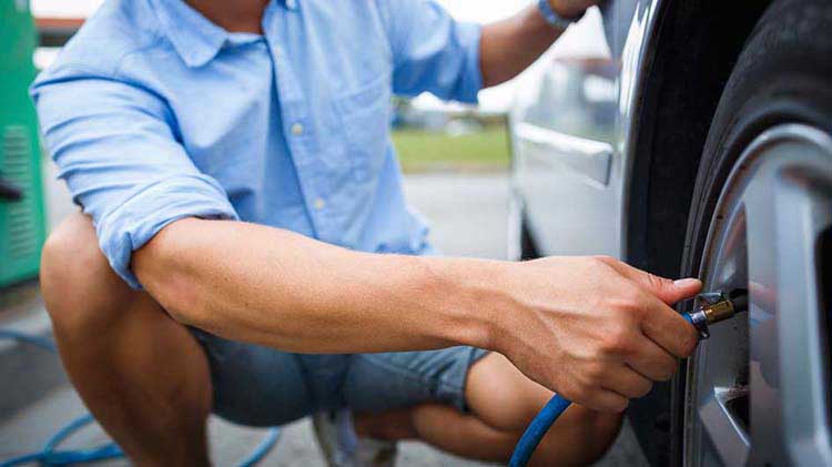 Man putting air in a car tire.