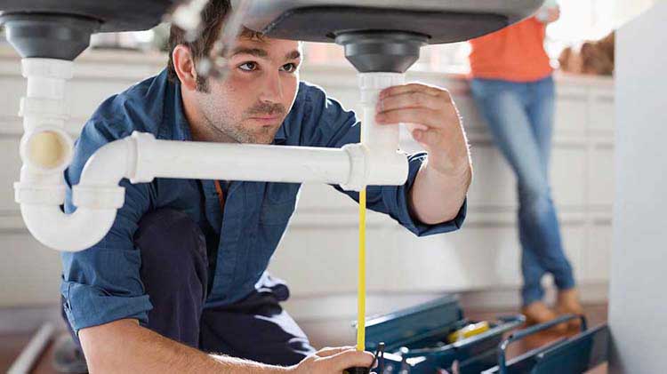 Man checking plumbing under a sink