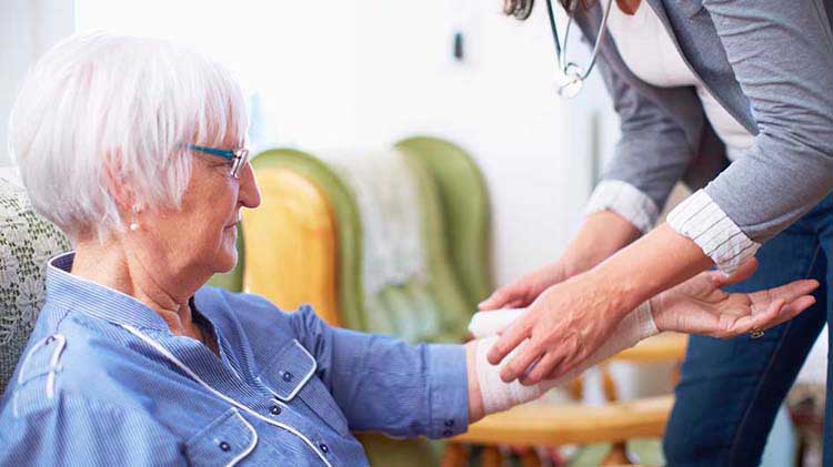 Woman having her arm bandaged by a health care provider.