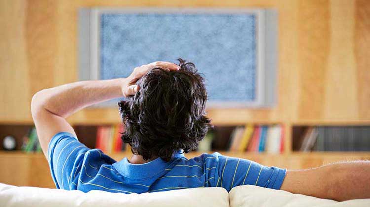 Man looking at static on a TV screen.