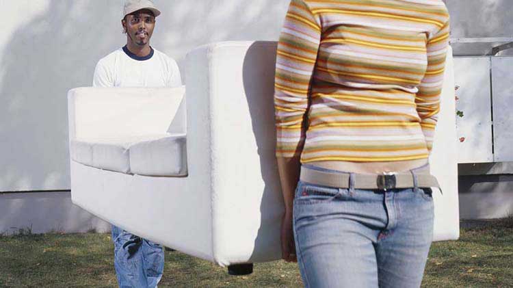 Two people carrying a couch after getting moving insurance.