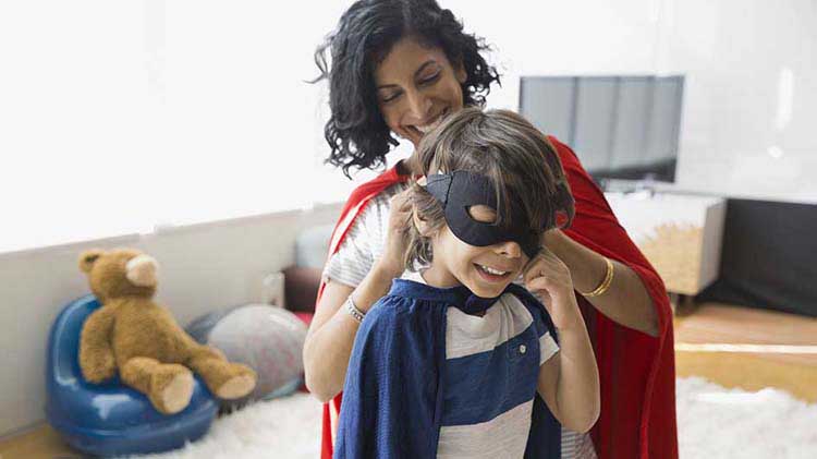 Mom helping her son put on a costume mask.