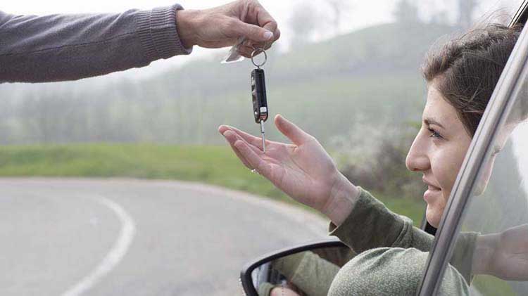 Parental hand dropping car keys into teen driver's hand.