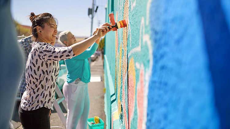 Women painting a wall while on a volunteer vacation.