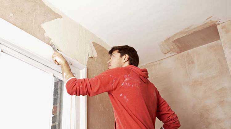 Contractor painting a wall after safely removing lead paint