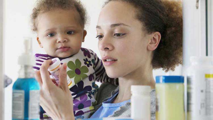 Mom with baby looking in medicine cabinet.