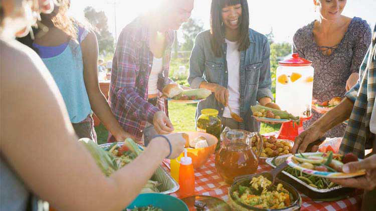 People loading up paper plates around a table at a cookout.