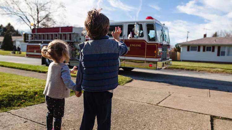 Kids waving at a fire truck after practicing their fire evacuation plan.