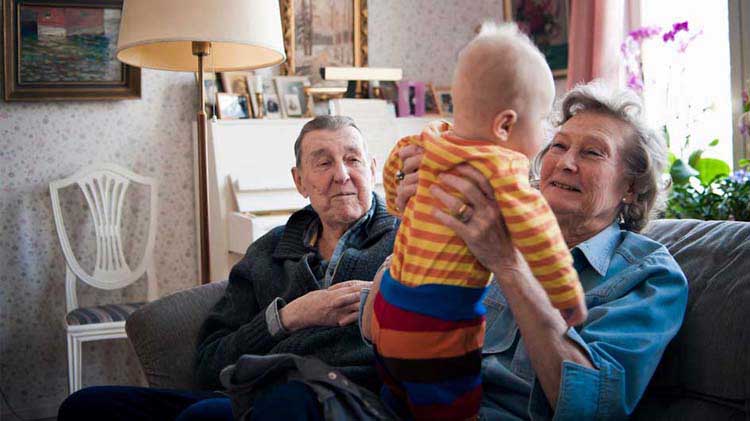 Grandparents with a baby on a couch.