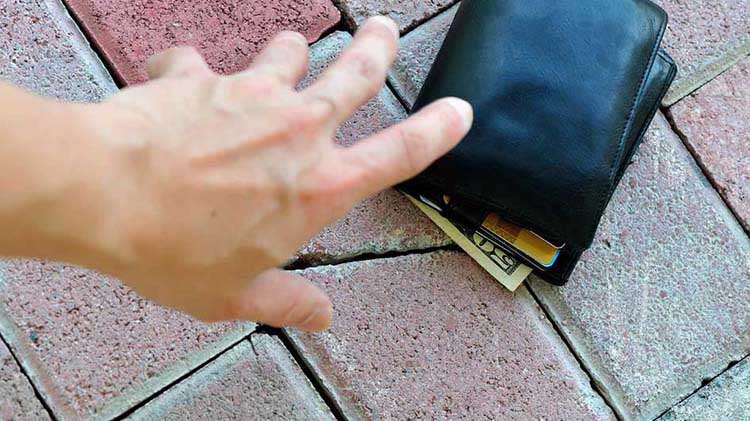 Hand reaching for wallet on ground.