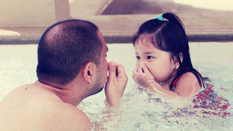 Dad practicing going underwater with daughter.