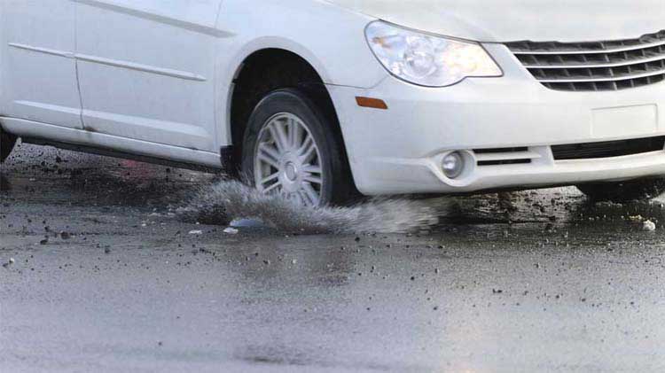 Car driving through a deep pothole.