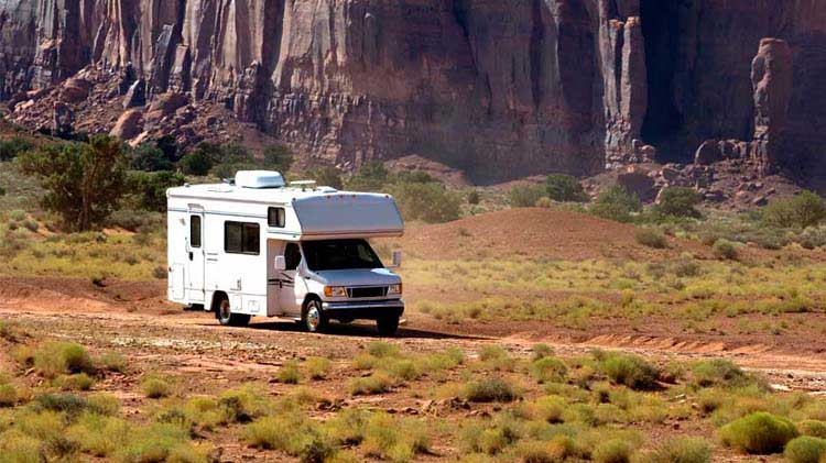 Family sitting around a campfire outside their RV.