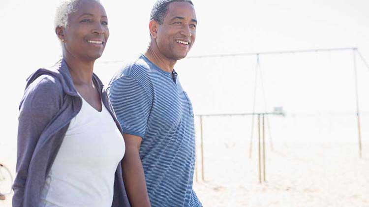 Older couple walking outside at the beach.