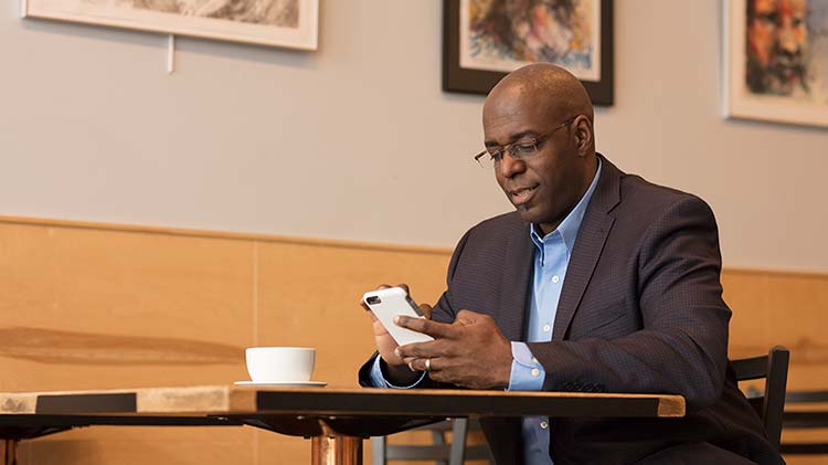 A man works on his phone at a cafe.