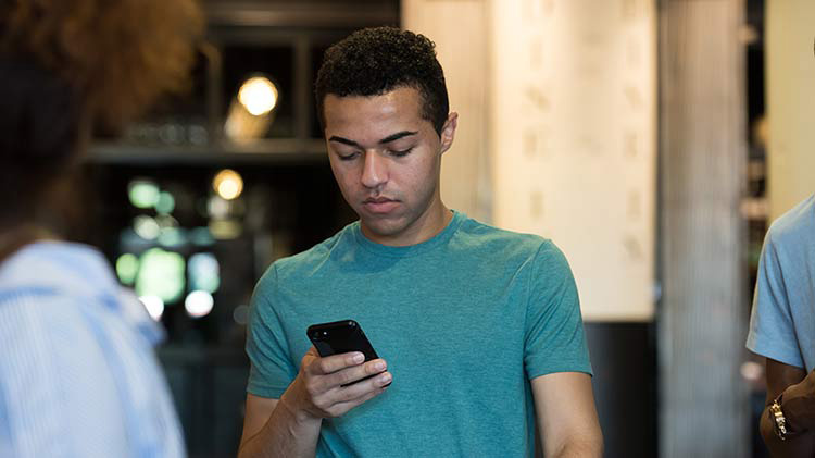 Young man looking at phone after receiving a spoofed call.