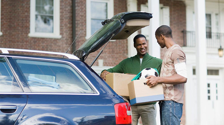 Dad and son unloading college supplies from car.