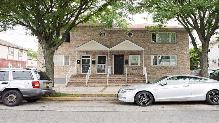 Brick condo building with vehicles parked in front.