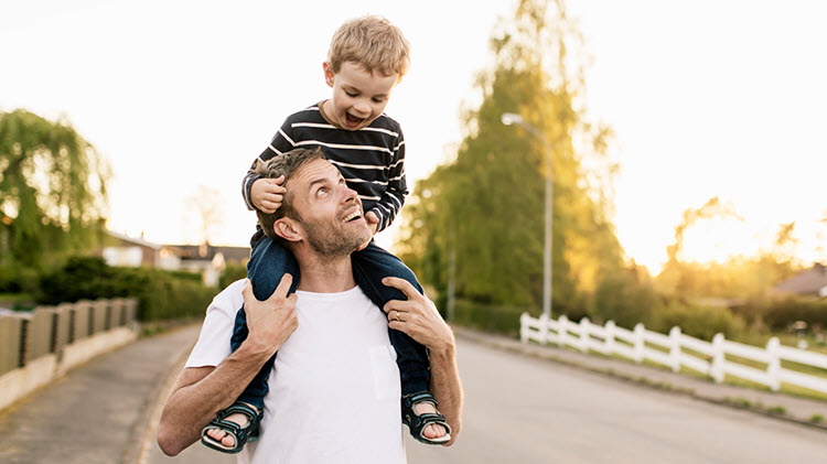 Dad carrying son on his shoulders.