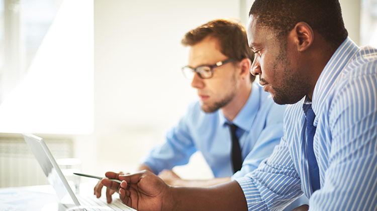 Two male employees are looking at a computer.