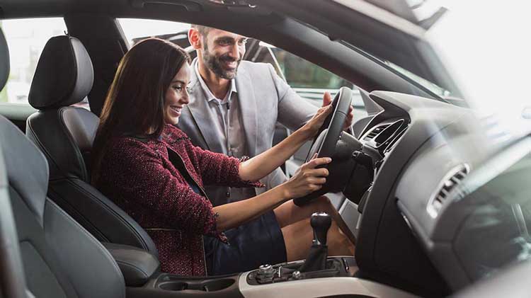 A young woman checking out a new car. 