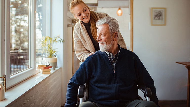 A woman pushing an older man in a wheelchair.