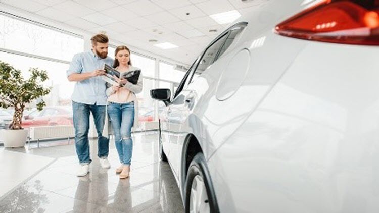 Couple at a dealership buying a car and deciding on their car loan term.