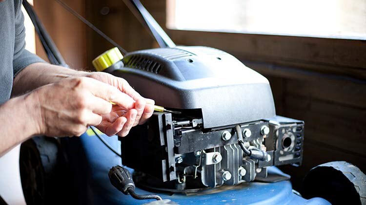 Person working on a lawn mower to get it ready for winter storage.