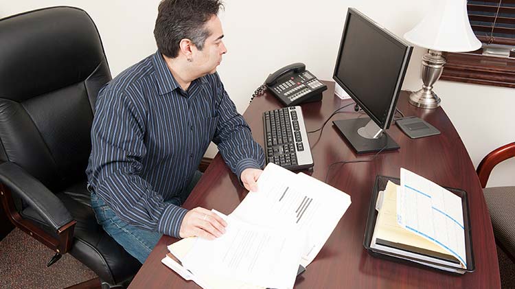 A small business owner sits at his desk working on his inventory