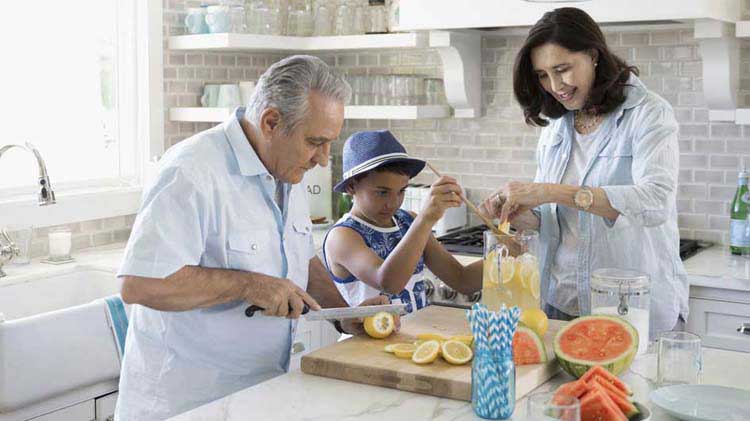 Family cutting up fruit in the kitchen.