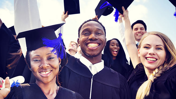 A group of young adults smiling after their college graduation ceremony.