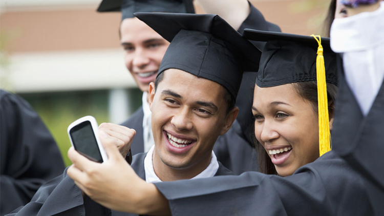 College graduates taking self-portrait together outdoors