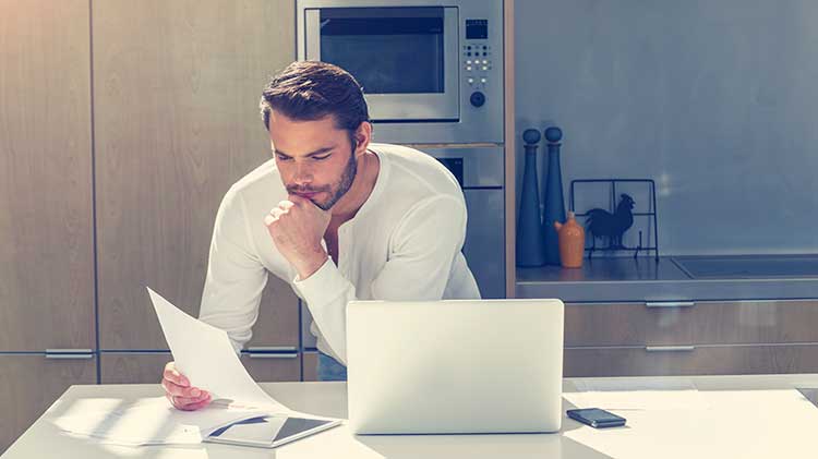 Gentlemen reading divorce paperwork in his kitchen.