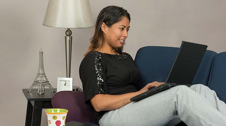 A woman reclines on the couch with her laptop completing a screen capture.