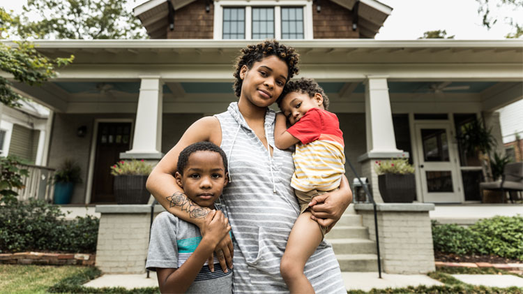 Portrait of a mother with her young children in front of a house. 