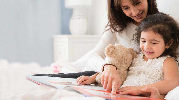 Woman reading to a child in bed.