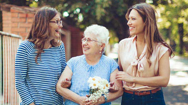 Three generations of women walking and talking about senior housing options.