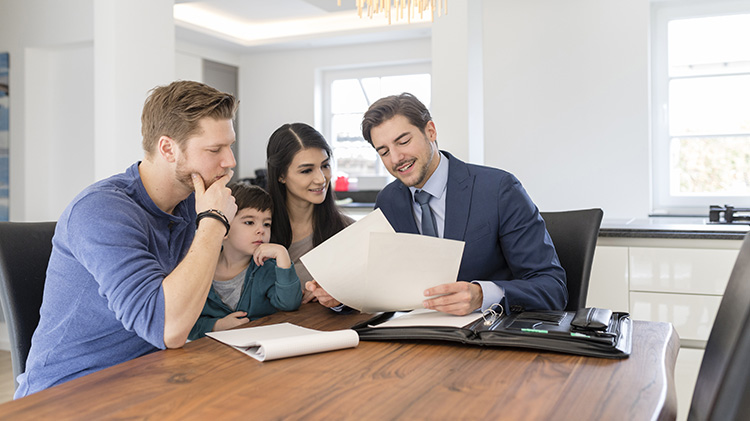 A young couple, along with their son, sit at the dining room table talking with an attorney.