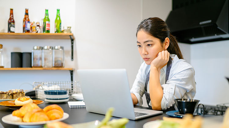 A woman sits at her computer thinking about her business.