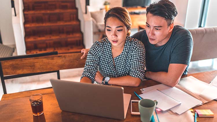 Couple figuring out a budget breakdown on their laptop.