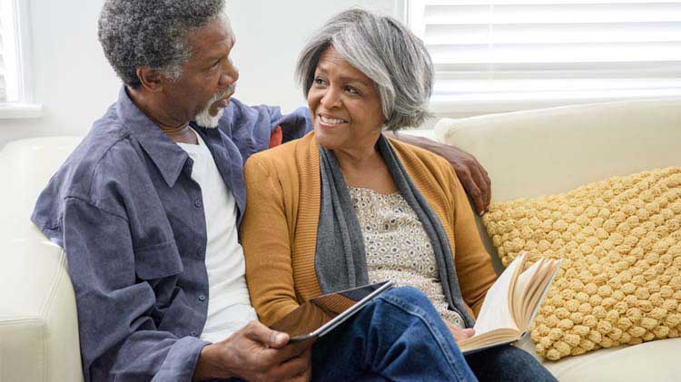 Elderly couple talking on a couch.