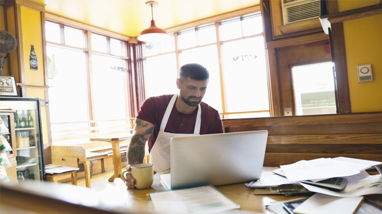 Small business owner reviewing his business goals on his laptop.