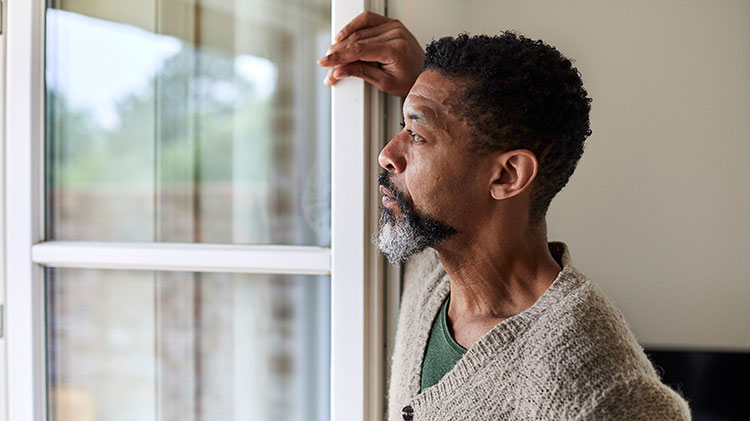 Man looking out the window considering post divorce finances.