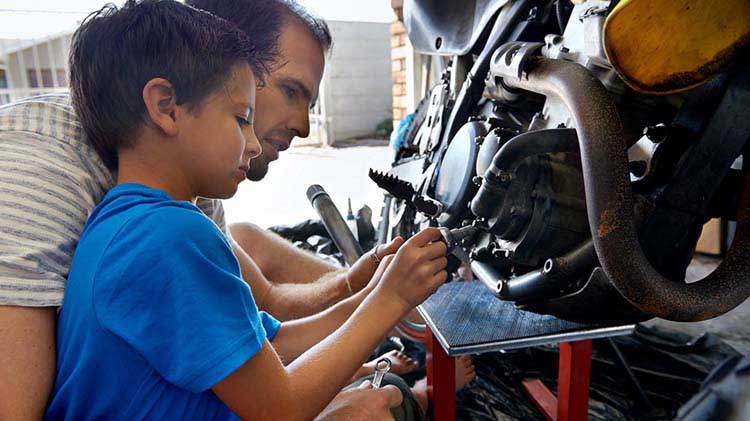 Father and child preparing to store a motorcycle