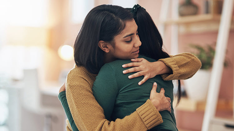 Two women sadly embracing