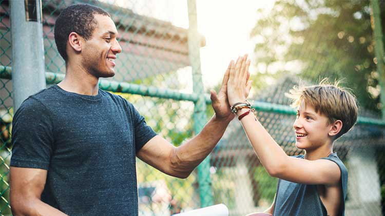 A mentor high fives a young boy.