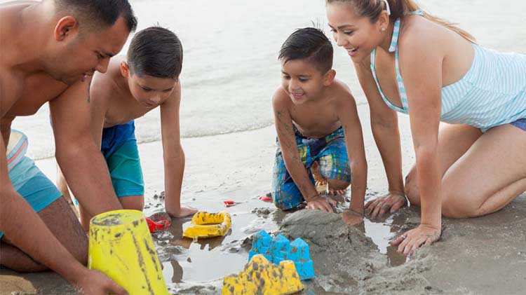 Family playing in the sand at the beach.