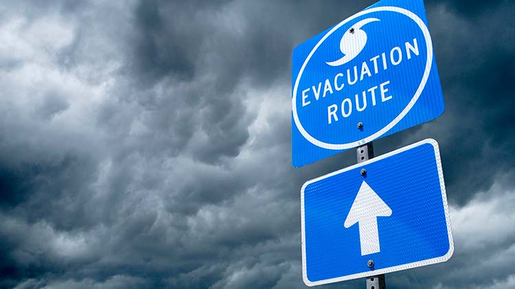 Hurricane evacuation route sign with storm clouds.